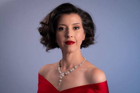 Lisette Oropesa in a red off-shoulder gown and pearl necklace, photo by Steven Harris